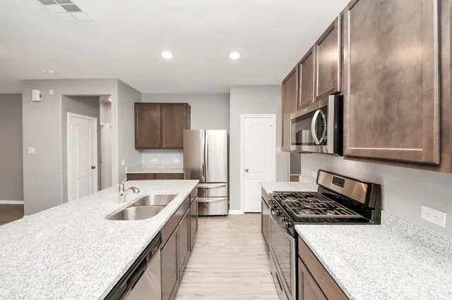 a kitchen with stainless steel appliances granite countertop a sink stove and refrigerator