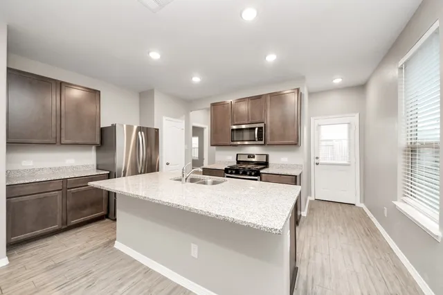 a kitchen with stainless steel appliances a microwave a sink a stove a refrigerator cabinets and a center island