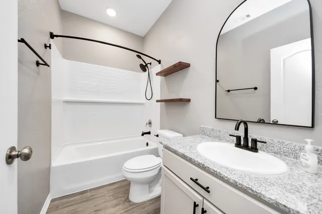 a bathroom with a granite countertop sink a toilet and shower