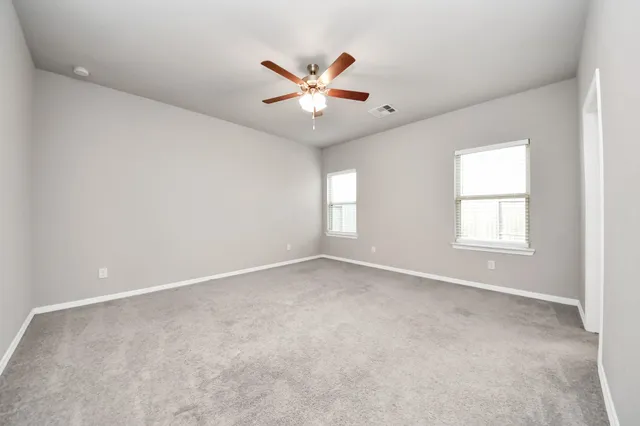 an empty room with windows and fan