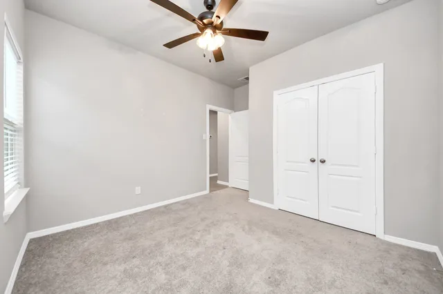 a view of an empty room and chandelier fan