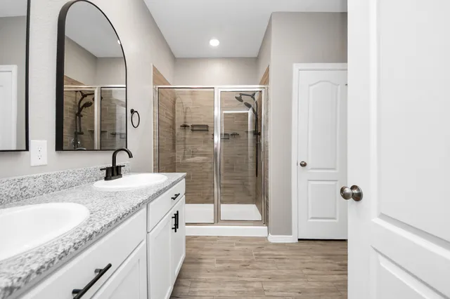 a spacious bathroom with a granite countertop sink a mirror and shower