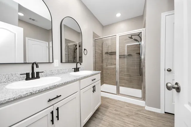 a bathroom with a granite countertop sink a mirror and shower