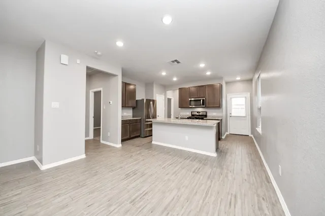 a view of kitchen with kitchen island granite countertop stainless steel appliances refrigerator oven stove top oven and cabinets
