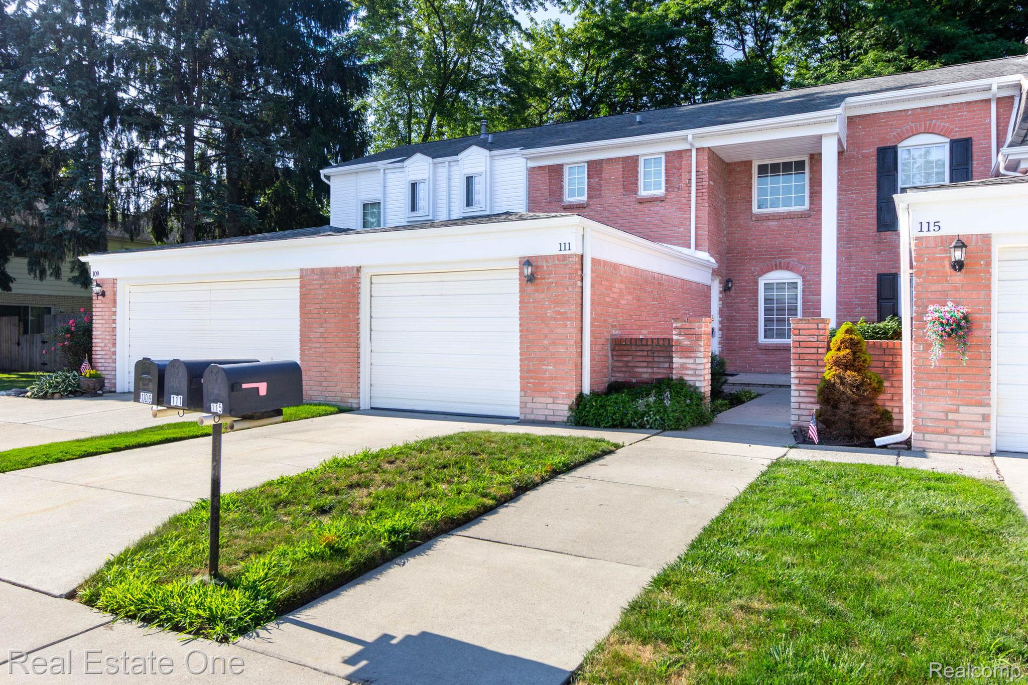 111 Manor Way Rochester, MI 48309 - Photo 2 of 36 Brick townhome residences featuring attached garages, white garage doors, and individual entryways