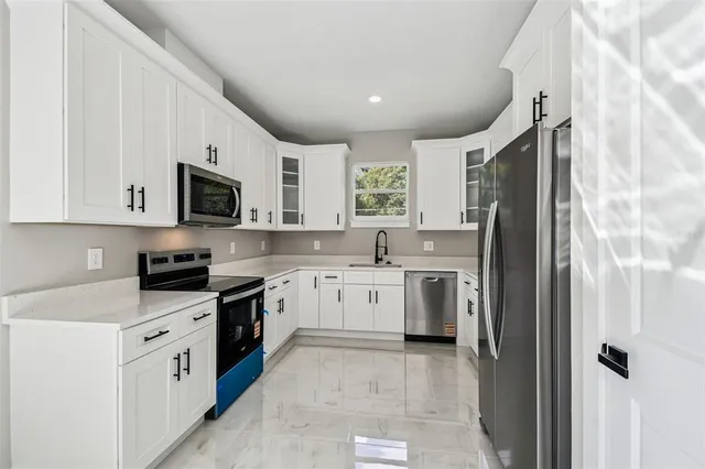 a kitchen with stainless steel appliances granite countertop white cabinets a sink and dishwasher