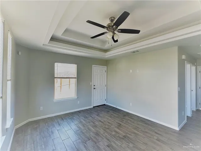 an empty room with wooden floor fan and windows