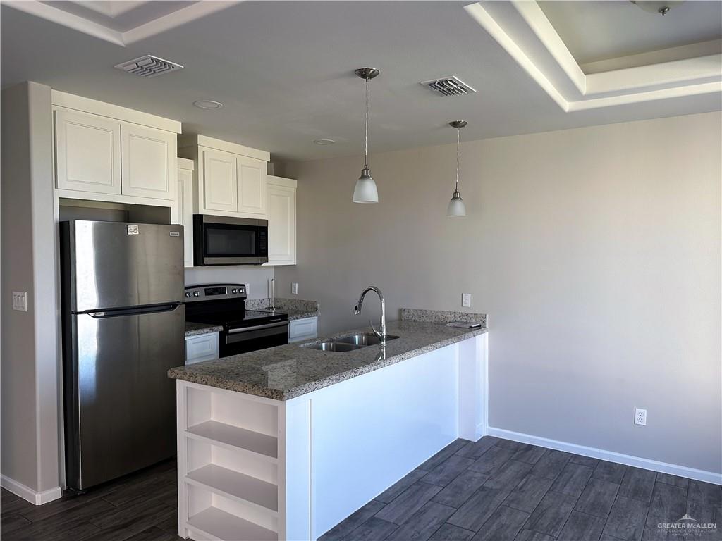 2210 Taxco Court, Unit 2 Edinburg, TX 78542 - Photo 4 of 7 a kitchen with a sink a microwave a refrigerator and white cabinets