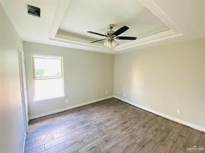 an empty room with wooden floor fan and windows