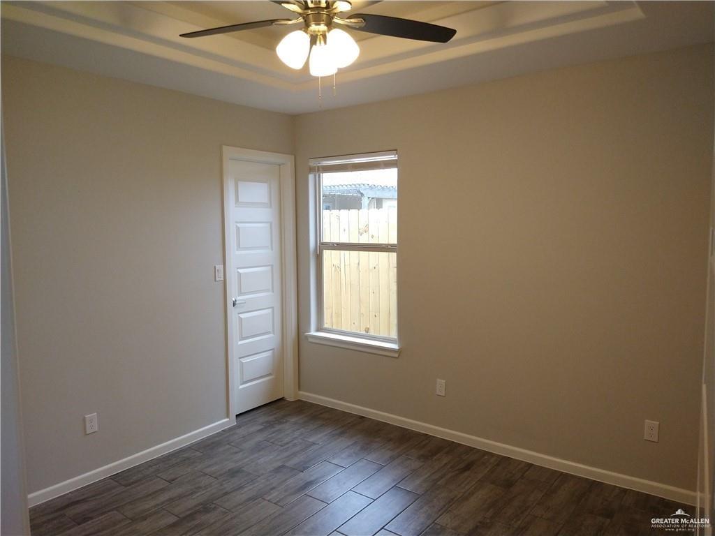 2210 Taxco Court, Unit 2 Edinburg, TX 78542 - Photo 7 of 7 an empty room with wooden floor chandelier fan and windows