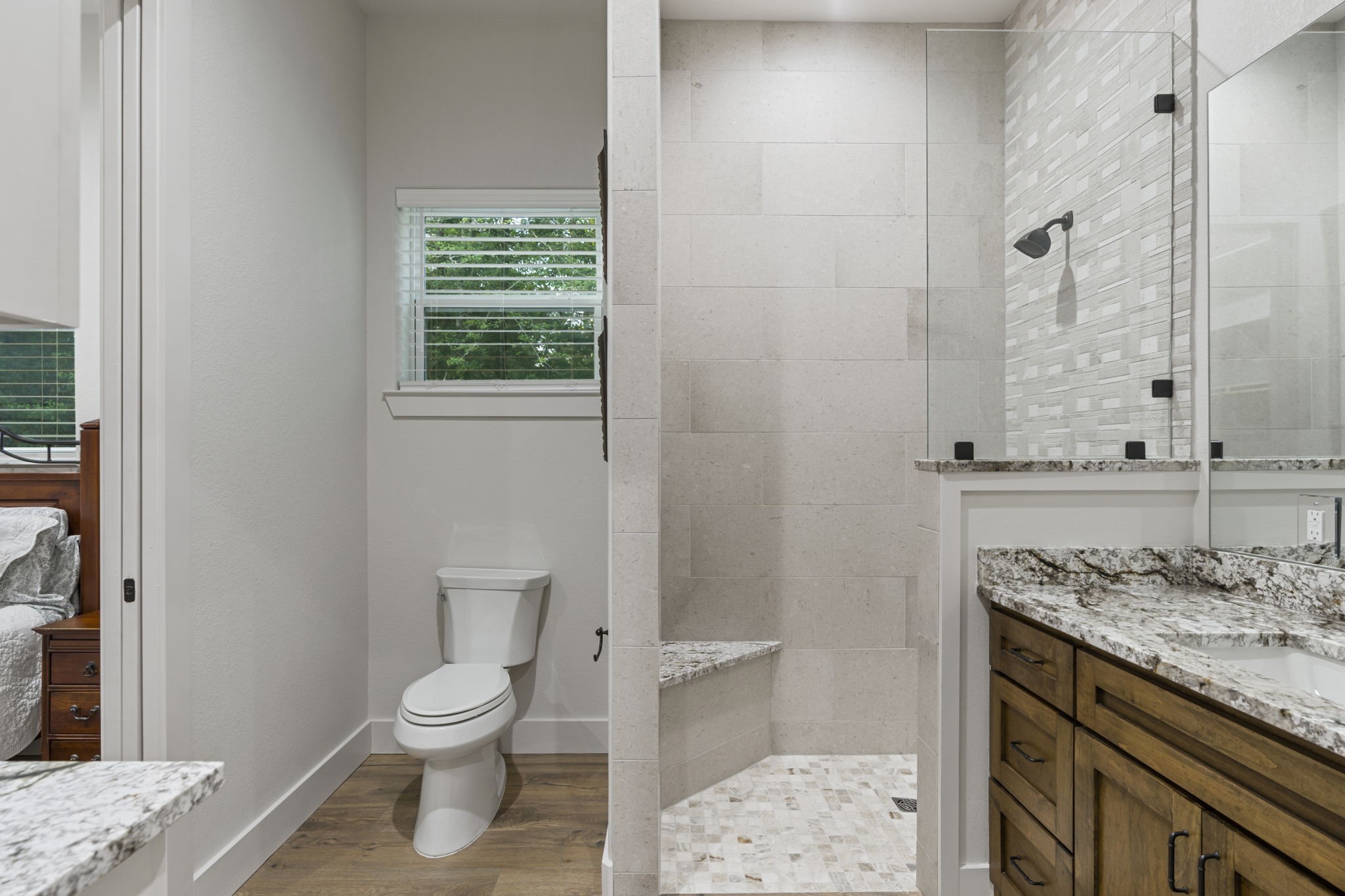 6970 Longmire Road Conroe, TX 77304 - Photo 29 of 48 a bathroom with a granite countertop toilet a sink and a mirror
