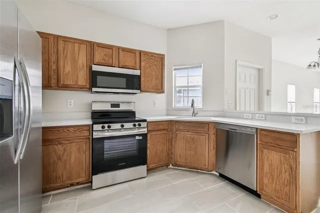 a kitchen with granite countertop wooden cabinets stainless steel appliances and a window