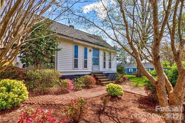 a backyard of a house with table and chairs under a large tree