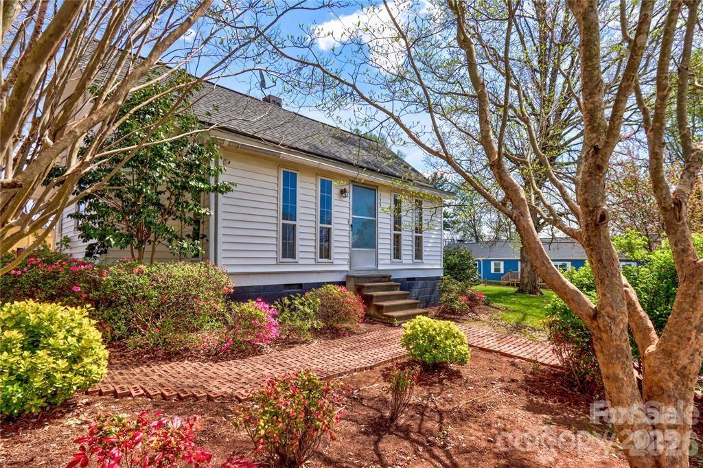 a backyard of a house with table and chairs under a large tree