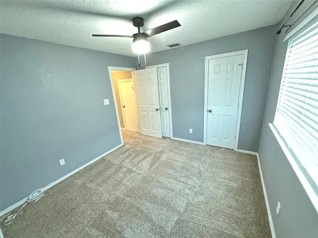 an empty room with a ceiling fan and a window