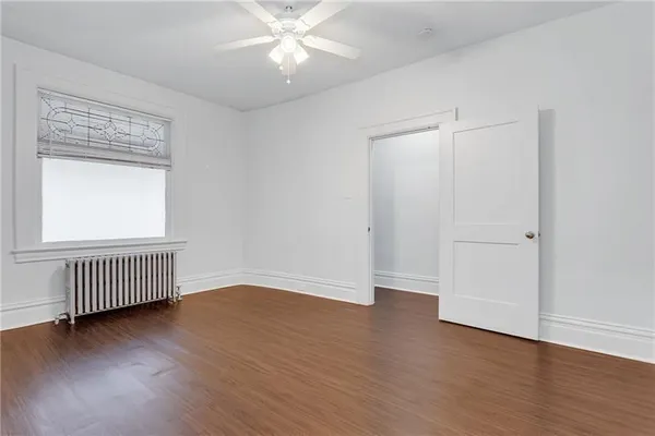 an empty room with wooden floor fan and windows