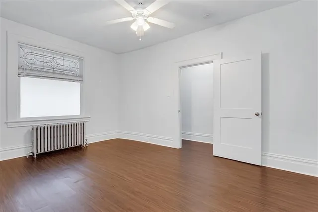an empty room with wooden floor fan and windows