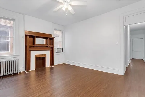 an empty room with wooden floor a fireplace and windows