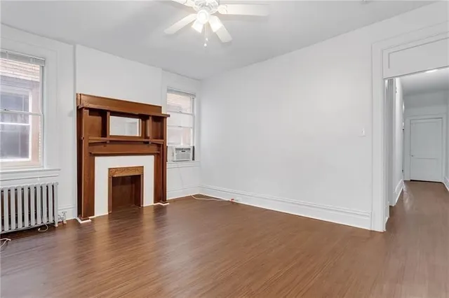 an empty room with wooden floor a fireplace and windows