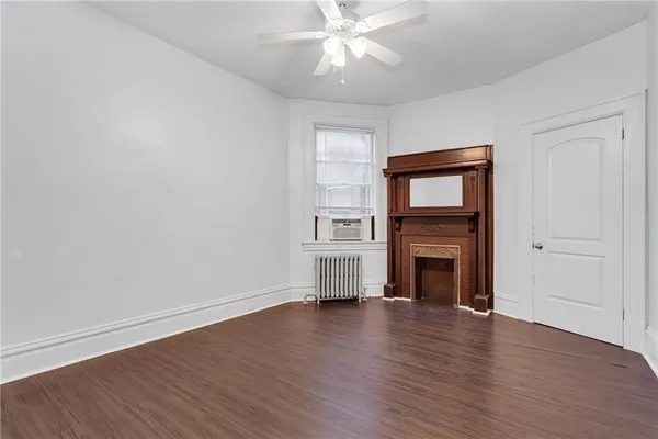 an empty room with wooden floor fireplace and windows