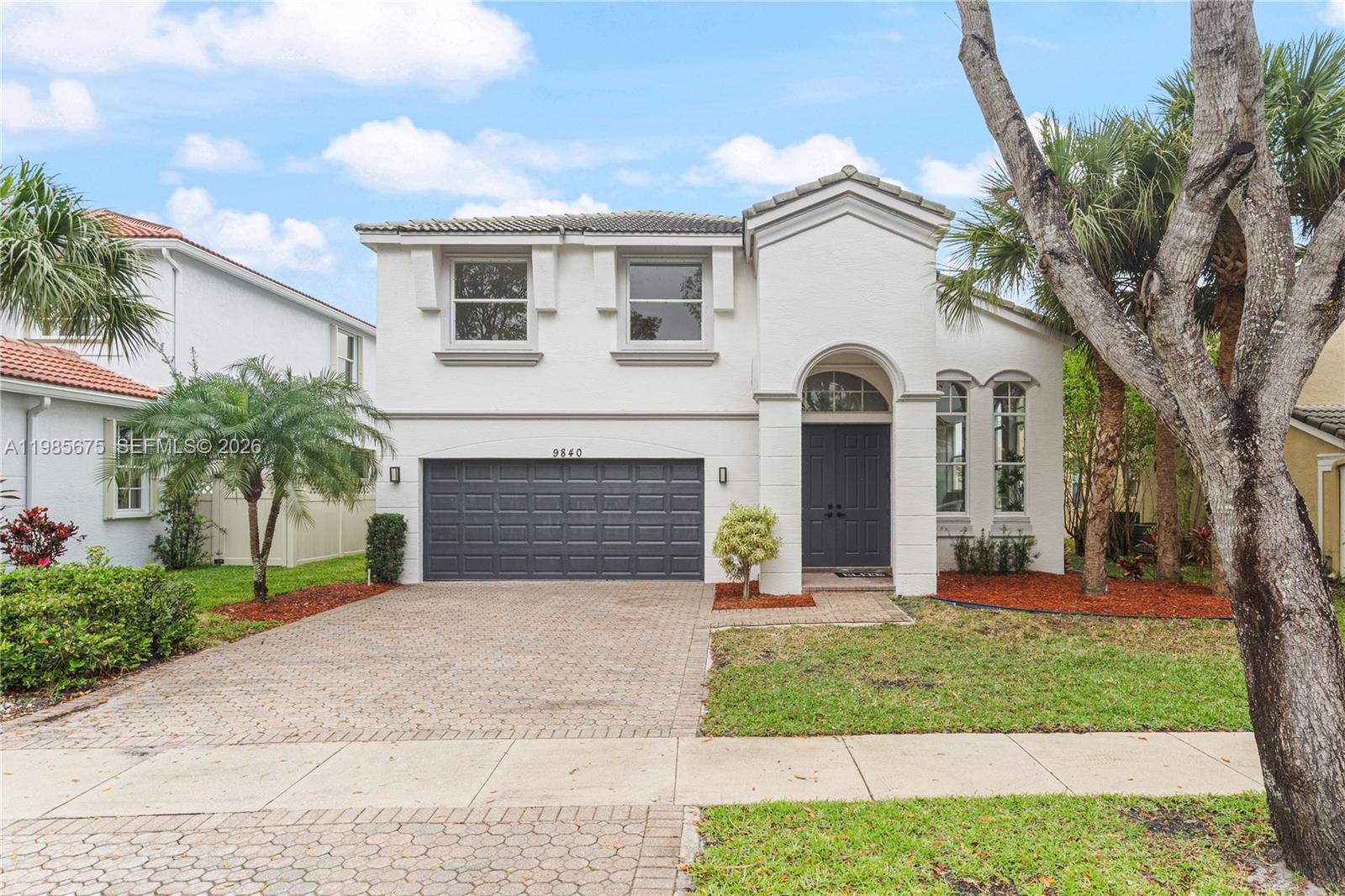 9840 Stover Way Wellington, FL 33414 - Photo 2 of 23 a front view of a house with a garden and trees