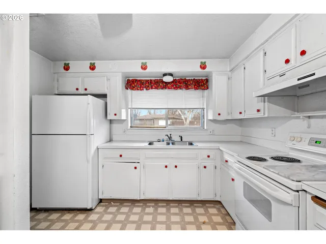 a kitchen with a sink a white refrigerator and white cabinets