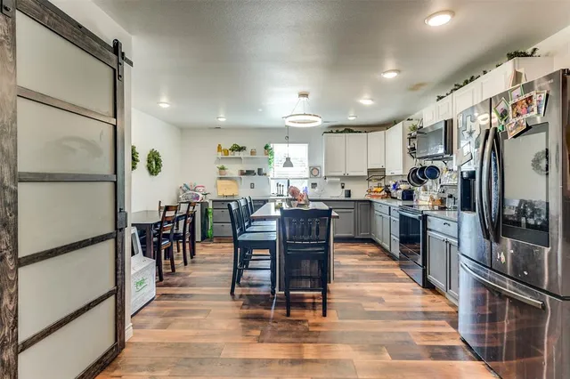 a kitchen with stainless steel appliances granite countertop a refrigerator dining table and chairs