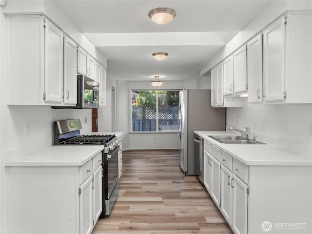 a kitchen with stainless steel appliances a stove a sink and white cabinets