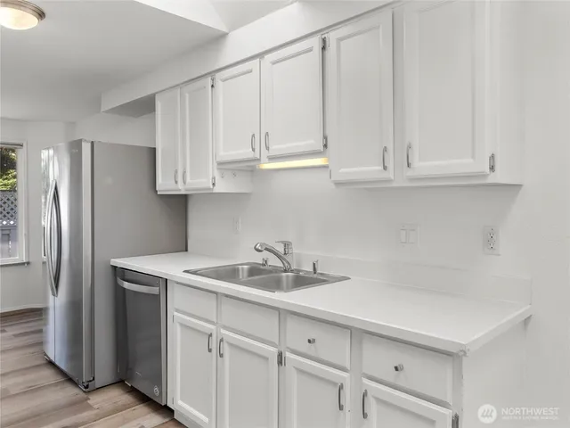 a kitchen with stainless steel appliances granite countertop white cabinets and a sink
