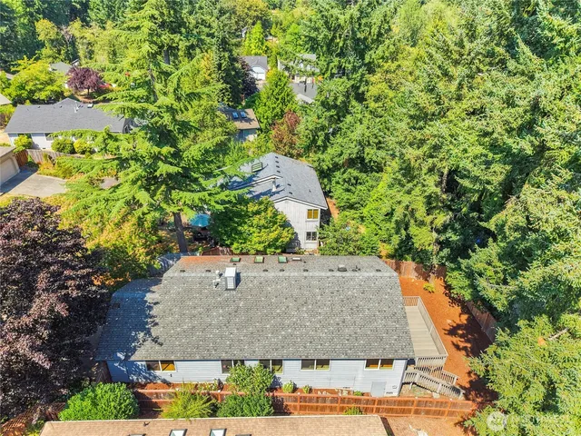 an aerial view of a house with yard and trees in the background