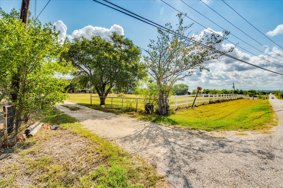 2411 Rohde Road Kyle, TX 78640 - Photo 12 of 40 Mature trees frame the gravel driveway leading into this spacious, fenced country property.