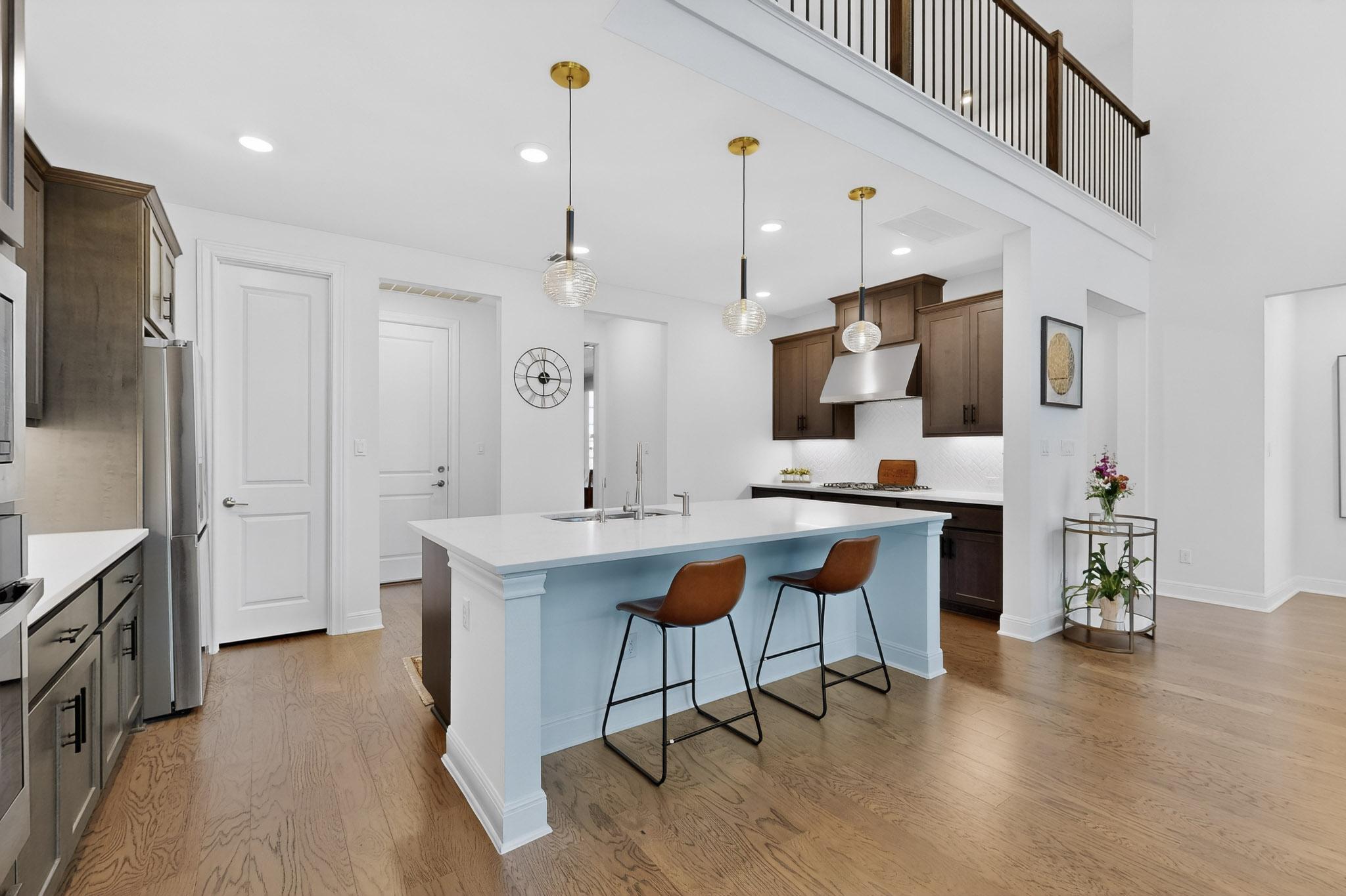 249 Running Bird Road Austin, TX 78737 - Photo 13 of 40 Kitchen featuring a center island with sink, a breakfast bar, light wood-style floors, hanging light fixtures, and stainless steel appliances