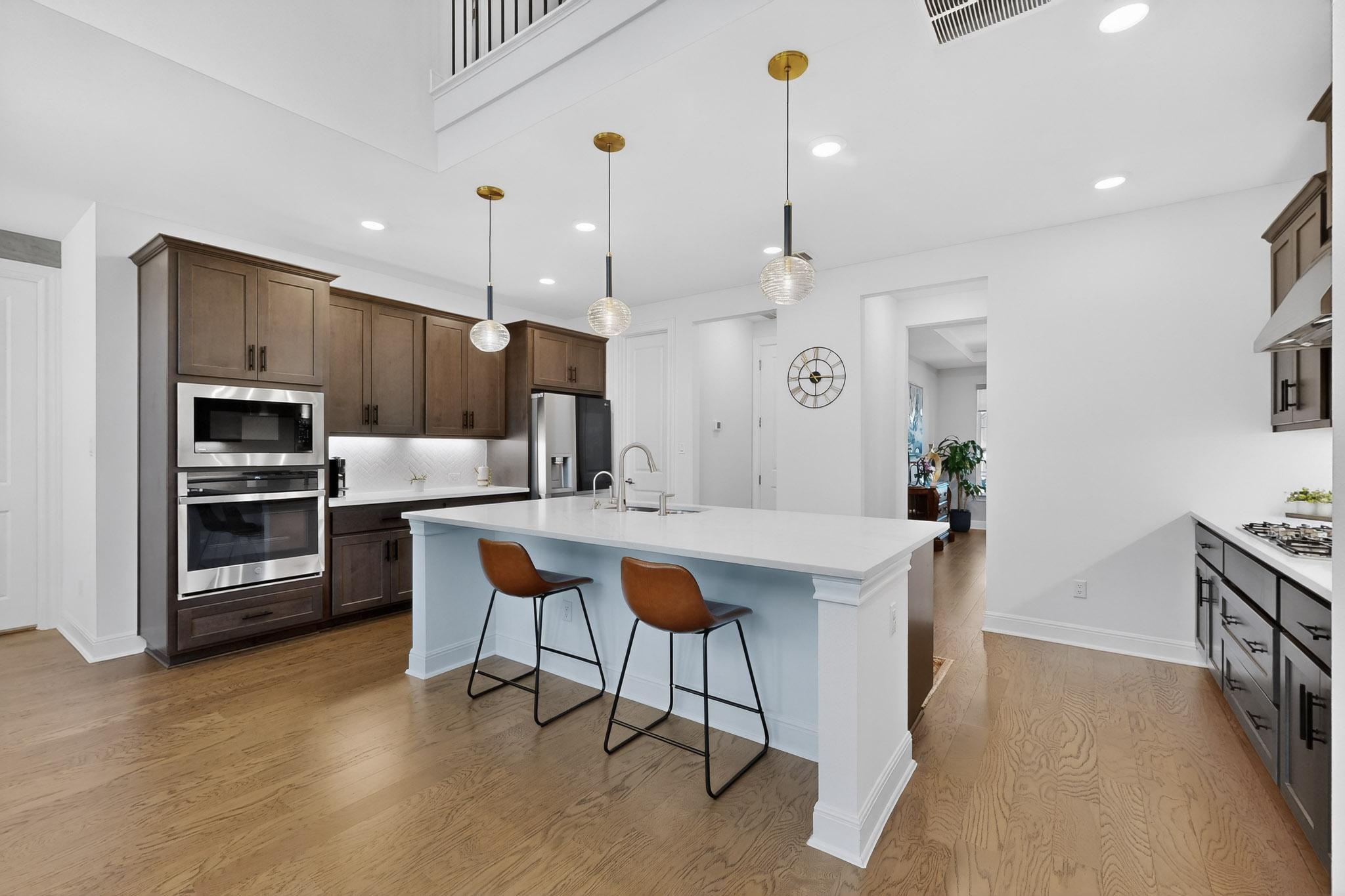 249 Running Bird Road Austin, TX 78737 - Photo 14 of 40 Kitchen with stainless steel appliances, light wood-style flooring, a kitchen island with sink, a breakfast bar, and decorative light fixtures