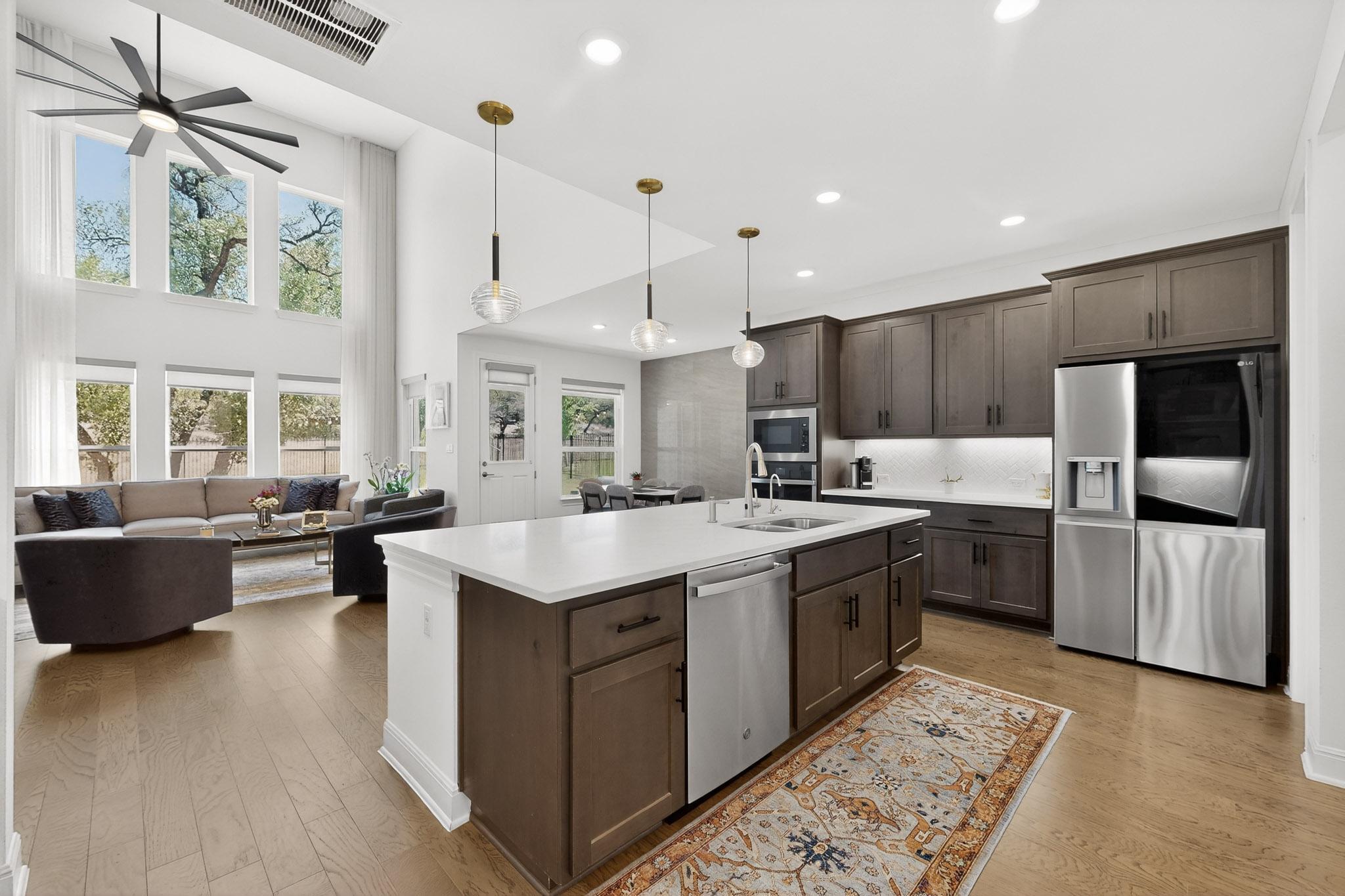 249 Running Bird Road Austin, TX 78737 - Photo 39 of 40 Kitchen with dark wood finish cabinets, stainless steel appliances, open floor plan, light wood-style flooring, and a high ceiling