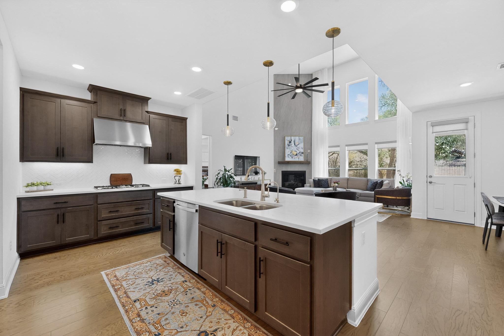 249 Running Bird Road Austin, TX 78737 - Photo 40 of 40 Kitchen featuring dark wood finish cabinets, open floor plan, light wood-style floors, a ceiling fan, and a high ceiling