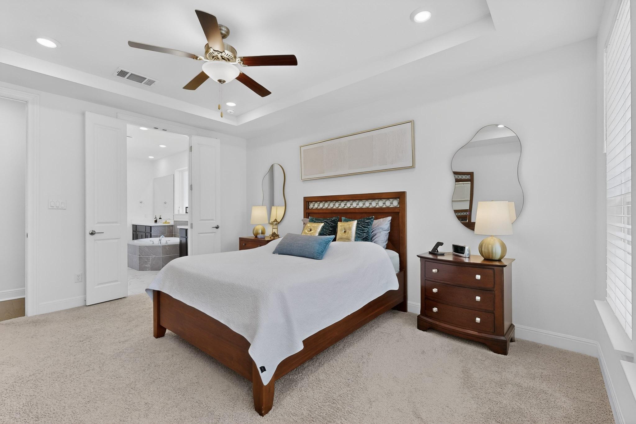 249 Running Bird Road Austin, TX 78737 - Photo 16 of 40 Primary Bedroom with light colored carpet, ceiling fan, a tray ceiling, recessed lighting, and connected bathroom