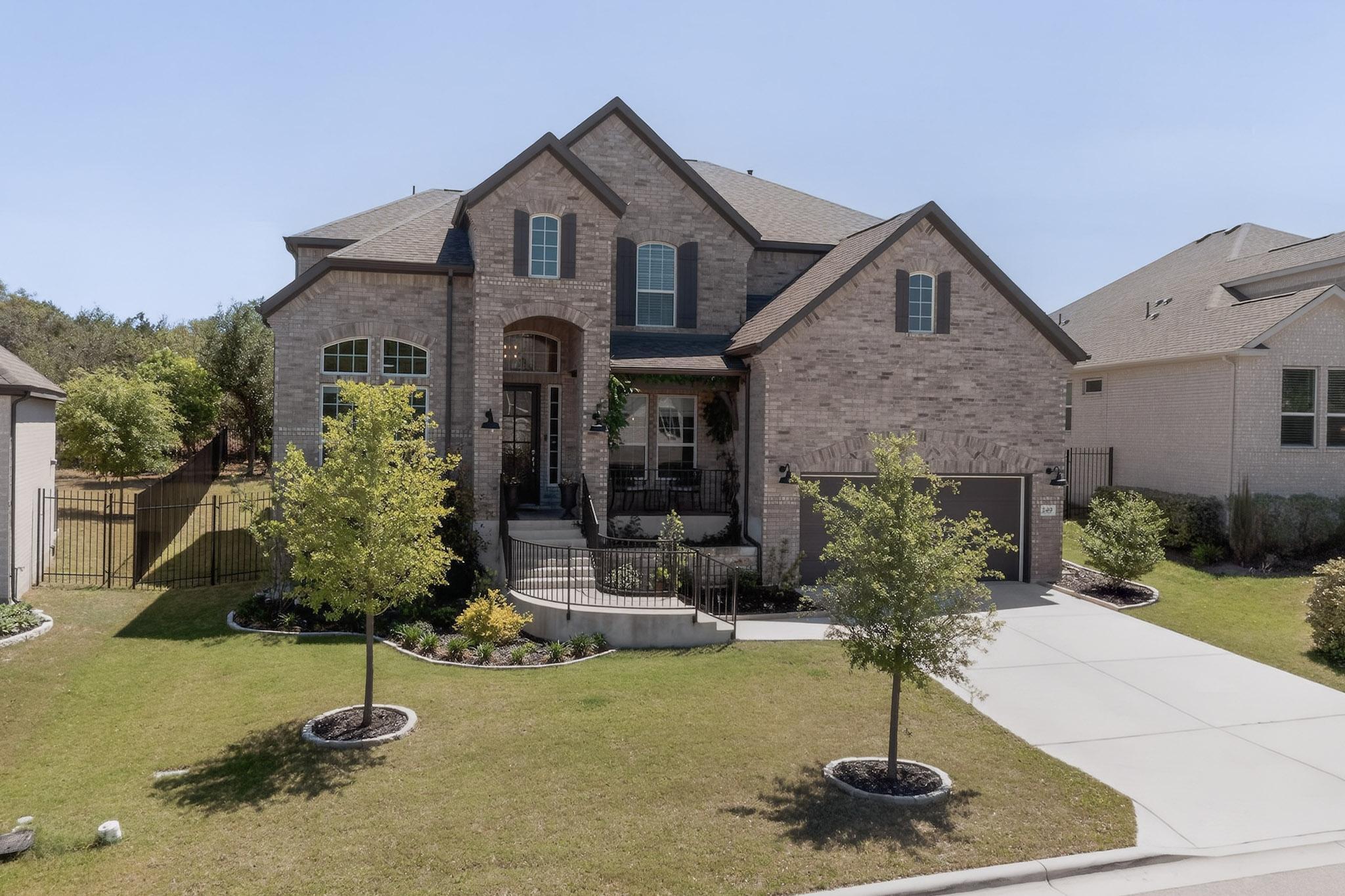 249 Running Bird Road Austin, TX 78737 - Photo 2 of 40 French country style house featuring brick siding, driveway, a front lawn, and an attached garage
