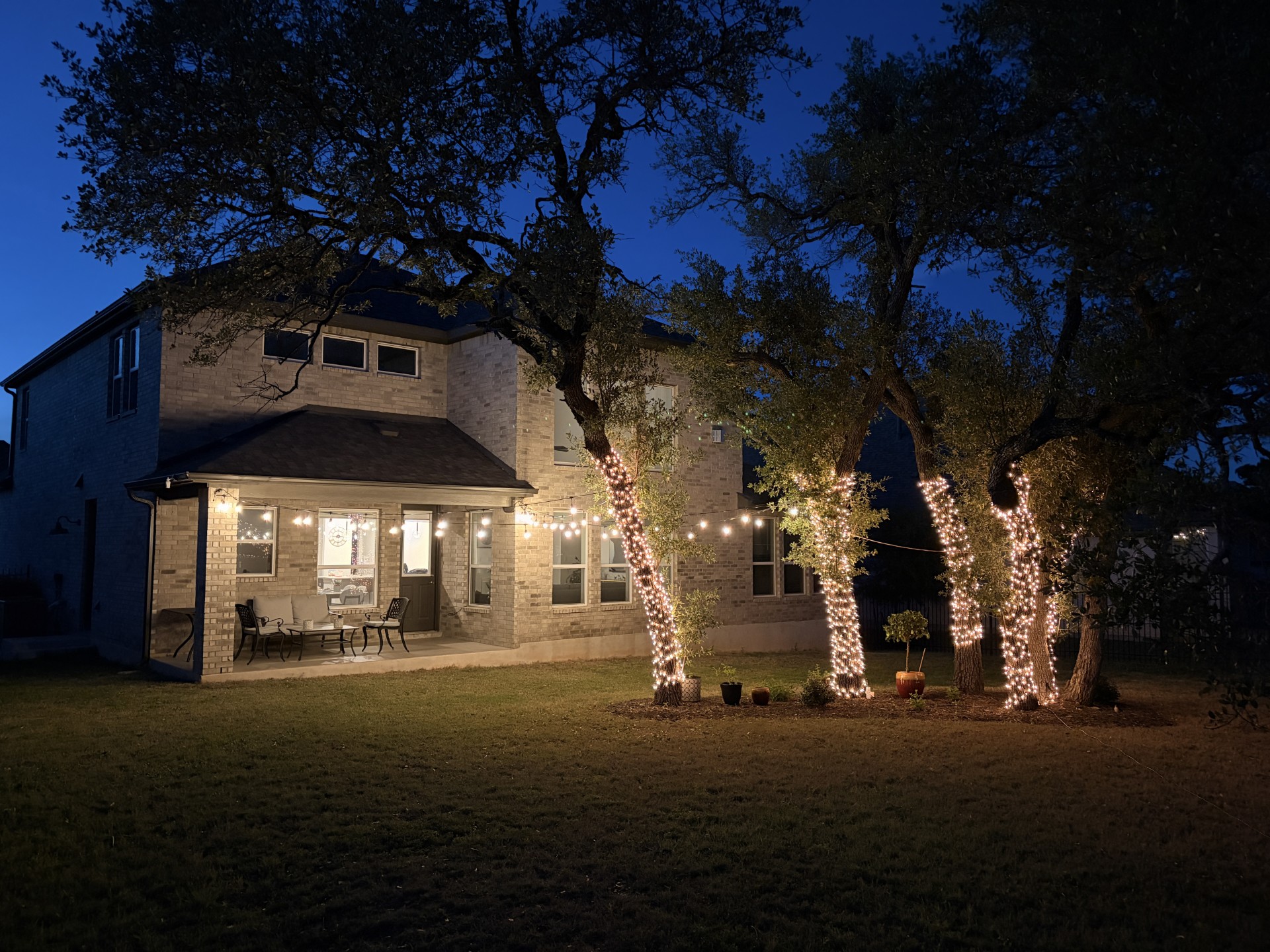 249 Running Bird Road Austin, TX 78737 - Photo 35 of 40 Back of house at night with a patio area, a yard, and brick siding