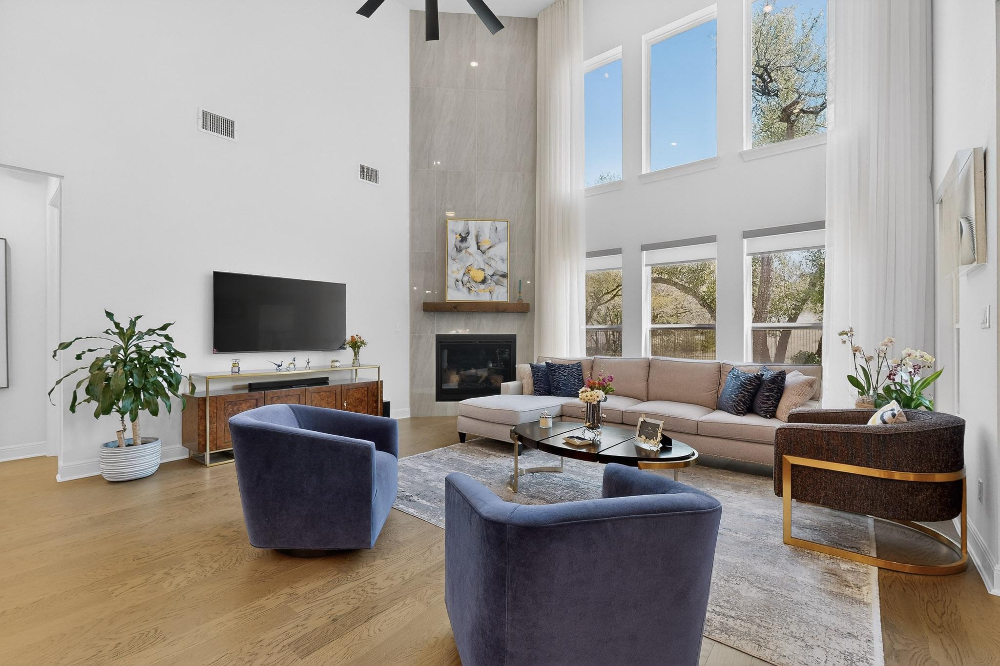 249 Running Bird Road Austin, TX 78737 - Photo 10 of 40 Living room with light wood-style flooring, a fireplace, a high ceiling, and a ceiling fan