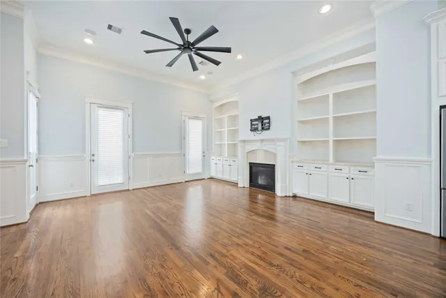 an empty room with wooden floor closet and windows