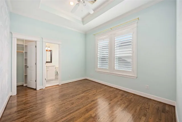 an empty room with wooden floor cabinet and windows