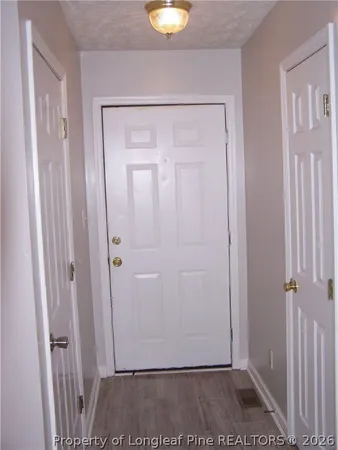 a view of an empty room with chandelier fan and wooden floor