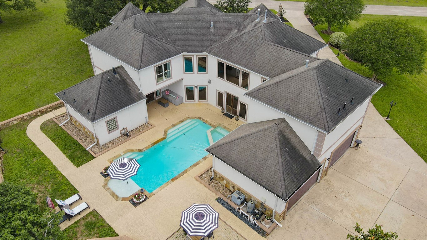 5610 Westerham Weston Lakes, TX 77441 - Photo 3 of 47 This aerial perspective showcases the pool perfectly positioned within the home’s distinctive U shaped design, creating a private outdoor retreat, while highlighting the expansive acre setting with mature trees.