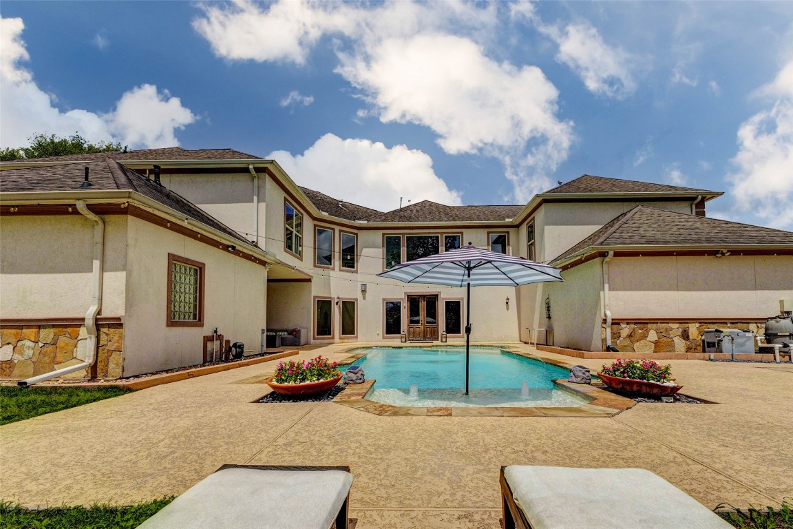 5610 Westerham Weston Lakes, TX 77441 - Photo 40 of 47 Step outside to your private backyard oasis, where a sparkling pool is framed by expansive patio space, offering the perfect setting for relaxing or entertaining while enjoying views of the home’s stunning exterior.