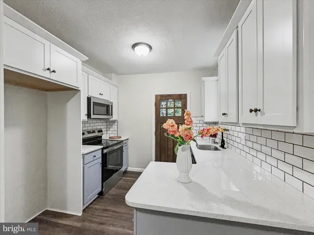 a kitchen with stainless steel appliances a sink a stove and white cabinets