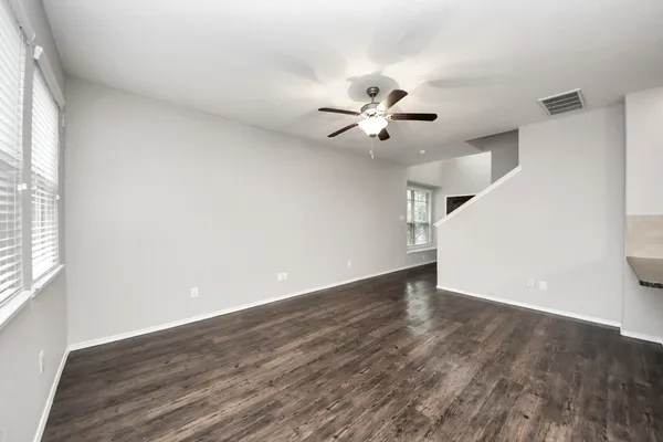 a view of an empty room with a window and wooden floor