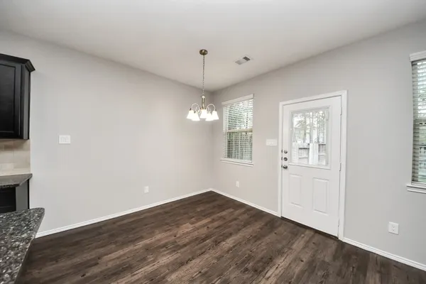 a kitchen with a chandelier and wooden floor