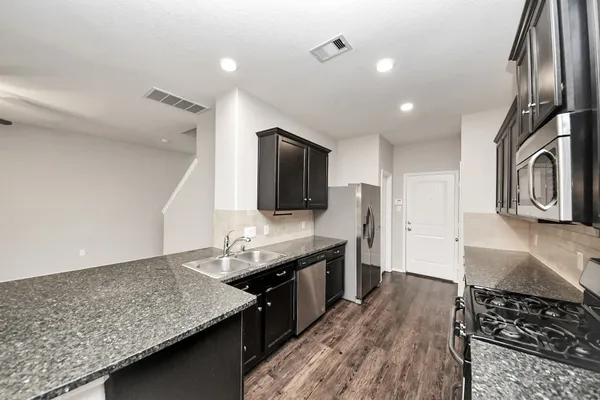 a kitchen with stainless steel appliances granite countertop a stove a sink and a microwave