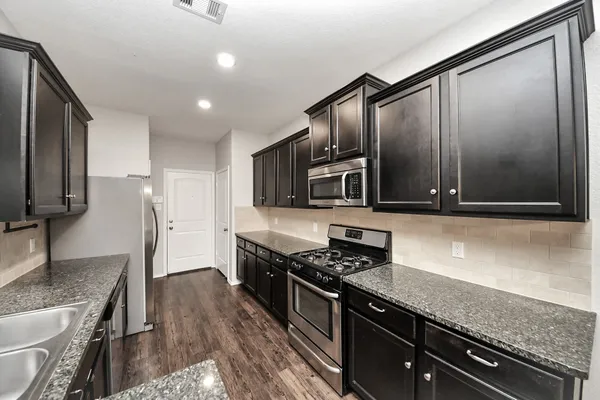 a kitchen with stainless steel appliances granite countertop a refrigerator and a sink