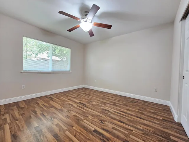 an empty room with wooden floor and windows
